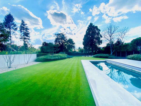 Produktbild von Kiepenkerl Golfrasen Masters Nachsaat tiefschnittverträglich zeigt gepflegten Rasen, Pool und Bäume im Hintergrund